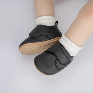 Détail de chaussures bébé en cuir noir avec velcro et semelles en caoutchouc souple