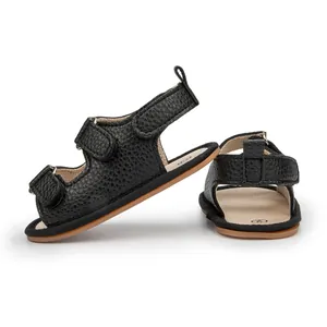 Dettaglio dei sandali per neonati in pelle nera con doppie cinghie in velcro regolabili