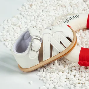 Detail of white leather baby sandal featuring woven straps and secure buckle closure