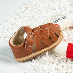Close-up of brown baby sandals showing textured leather straps and metal buckle detail