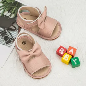 Pink baby girl walking sandals with bow decoration on soft white knitted blanket