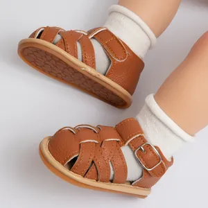 Detail of baby brown leather sandals featuring braided straps and non-slip textured sole