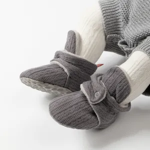Details von grauen Strick-Babyschuhen mit rutschfester Noppensohle und Plüschbesatz