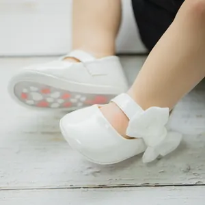 Dettaglio di scarpe Mary Jane bianche per neonata con fiocco e suola antiscivolo a cuori