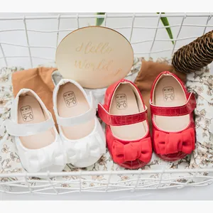Rote und weiße Baby-Prinzessinenschuhe mit großen Schleifen in einem Dekokorb