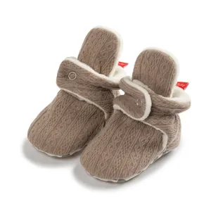 Detail der warmen braunen Strick-Babyschuhe mit weißem Fleecefutter und Knopfverschluss