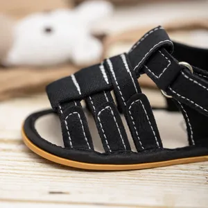 Detail of black fabric baby sandals with white stitching and hook-and-loop closure