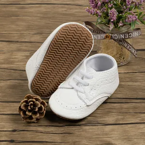 Close-up of white baby walker shoes with textured leather and brown anti-slip rubber soles