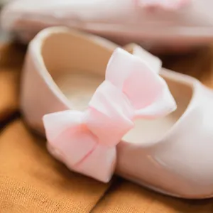 Dettaglio di scarpe Mary Jane rosa neonato in vernice con fiocco di raso