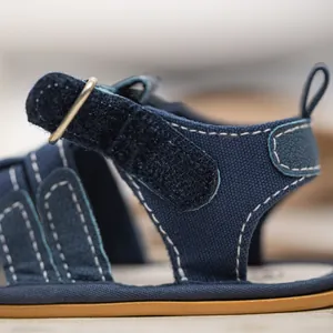 Close-up of navy canvas baby sandals showing white stitching and velcro strap details