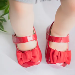 Nahaufnahme der roten Baby-Mary-Jane-Schuhe aus Lackleder mit großer Schleife und Klettverschluss