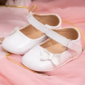 Detail of white PU leather baby Mary Janes with glittery bow and velcro strap