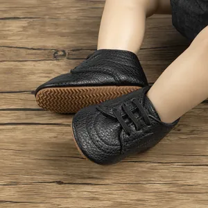Detailed view of black synthetic leather baby shoes with anti-slip rubber wavy soles