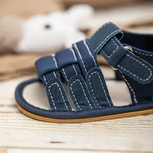 Close-up of navy baby sandals showing white stitching and breathable hollow cage design