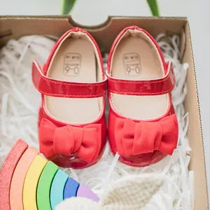 Makroaufnahme roter Baby-Lackschuhe mit Schleife in Geschenkbox für 0-6 Monate