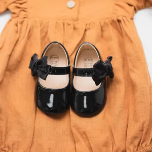 Dettaglio di scarpe per neonati in vernice nera con fiocchi e taglia 0-6 mesi