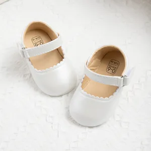 Detail of white Mary Jane baby shoes with scalloped edges and Velcro strap for infants