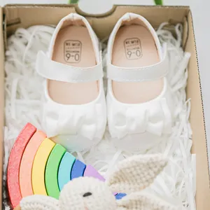 Nahaufnahme weißer Babyschuhe mit Schleife und Klettverschluss in einer Geschenkbox