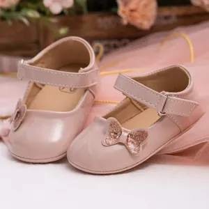Close-up of pink patent leather baby shoes with glitter bow and velcro strap