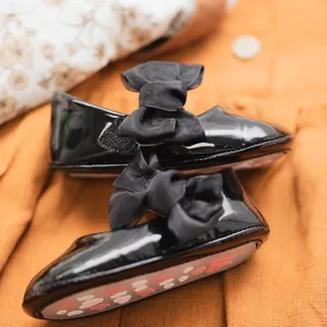 Dettaglio scarpe Mary Jane neonata in pelle verniciata nera con fiocco e suola antiscivolo