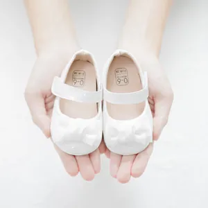 Detail von weißen Mary-Jane-Babyschuhen mit Schleife und Größenangabe 0-6 Monate