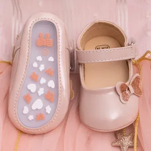 Detail of pink PU leather baby shoes with non-slip rubber soles and glittery bows