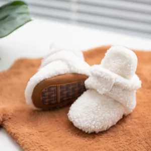 Detail of white sherpa baby booties with soft anti-slip sole and velcro closure