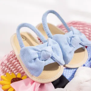 Detail of light blue baby sandal with a large bow and soft textured sole design