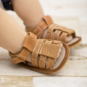 Detail of brown baby sandals with cutout straps, white stitching, and velcro closure