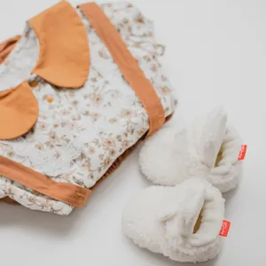 Close-up of baby floral dress and plush coral fleece shoes on white background