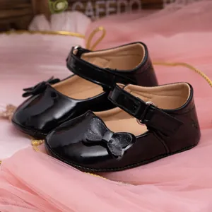 Detail of baby princess shoes in black patent leather with sparkling bow decoration