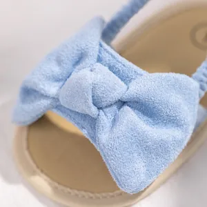 Close-up of soft blue faux suede baby sandals featuring a decorative oversized bow