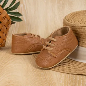 Detailed close-up of brown PU leather baby shoes with fine stitching on wood floor