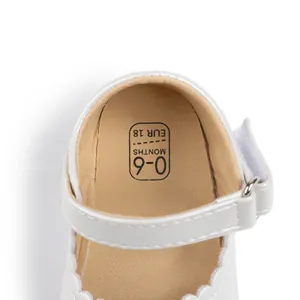 Macro detail of white baby Mary Jane shoe showing the scalloped edges and size marking