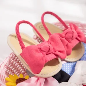 Detailed close-up of pink baby sandal with large bow decoration and elastic heel strap