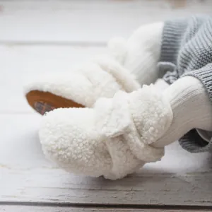 Close-up of baby warm boots featuring soft white fleece texture and durable non-slip brown soles
