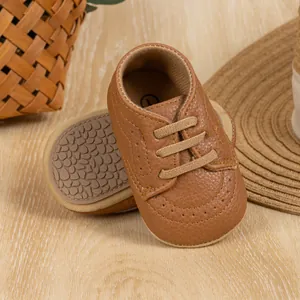 Close-up of brown leather baby walking shoes with non-slip sole on wooden background