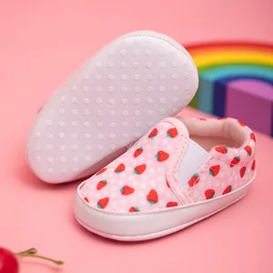 Detail showing pink canvas baby loafers with strawberry print and anti-slip dotted soft soles