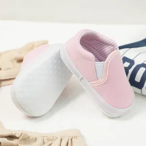 Pink canvas baby loafer showing soft white non-slip sole with dotted grip details
