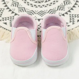 Close-up of pink baby canvas walking shoes with striped lining and elastic straps