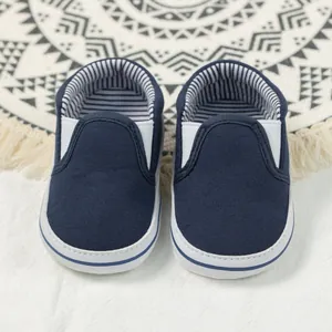 Detail view of navy canvas baby loafers with striped lining and white rubber soles