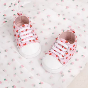Detailed top view of pink baby loafer featuring red strawberry prints and protective white toe cap
