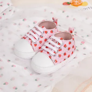 Close-up of pink baby canvas shoes with strawberry prints and soft white laces