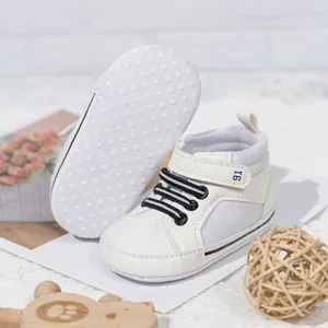 Close-up of white baby pre-walkers featuring non-slip dot soles and velcro straps