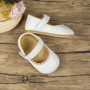 Detailweergave van witte Mary Jane babyschoentjes met goudkleurige golvende rand