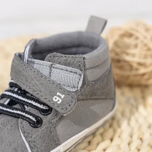 Detail of high-top baby shoes with grey PU leather, striped laces and Velcro closure
