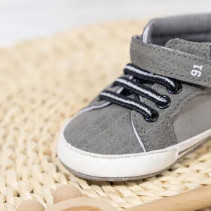 Detail of high-top baby walking shoes with grey textured leather and velcro strap