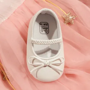 Gros plan de chaussures bébé Mary Jane blanches avec nœud et sangle élastique