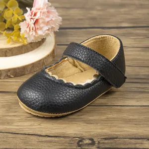 Detailopname van zwarte baby schoentjes met lychee leerstructuur en golvende randen
