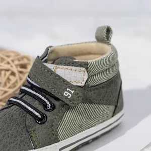 Detail of high-top baby walker shoes with olive green leather texture and magic tape